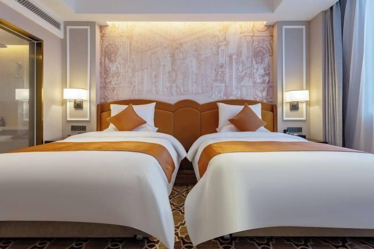 Ein Hotelzimmer mit zwei Betten, einer Wand mit Muster und Nachttischlampen.