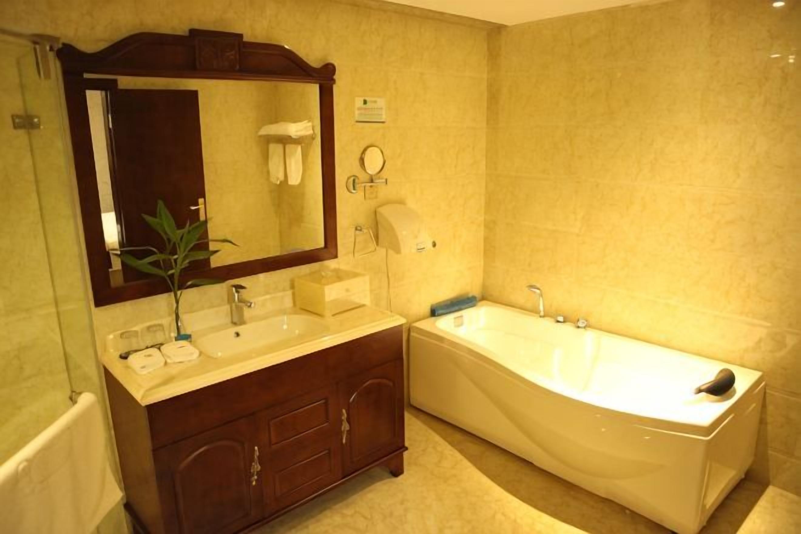 A bathroom with a double sink vanity, a large mirror, a bathtub, and a towel rack.