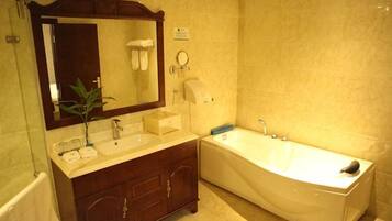 A bathroom with a double sink vanity, a large mirror, a bathtub, and a towel rack.