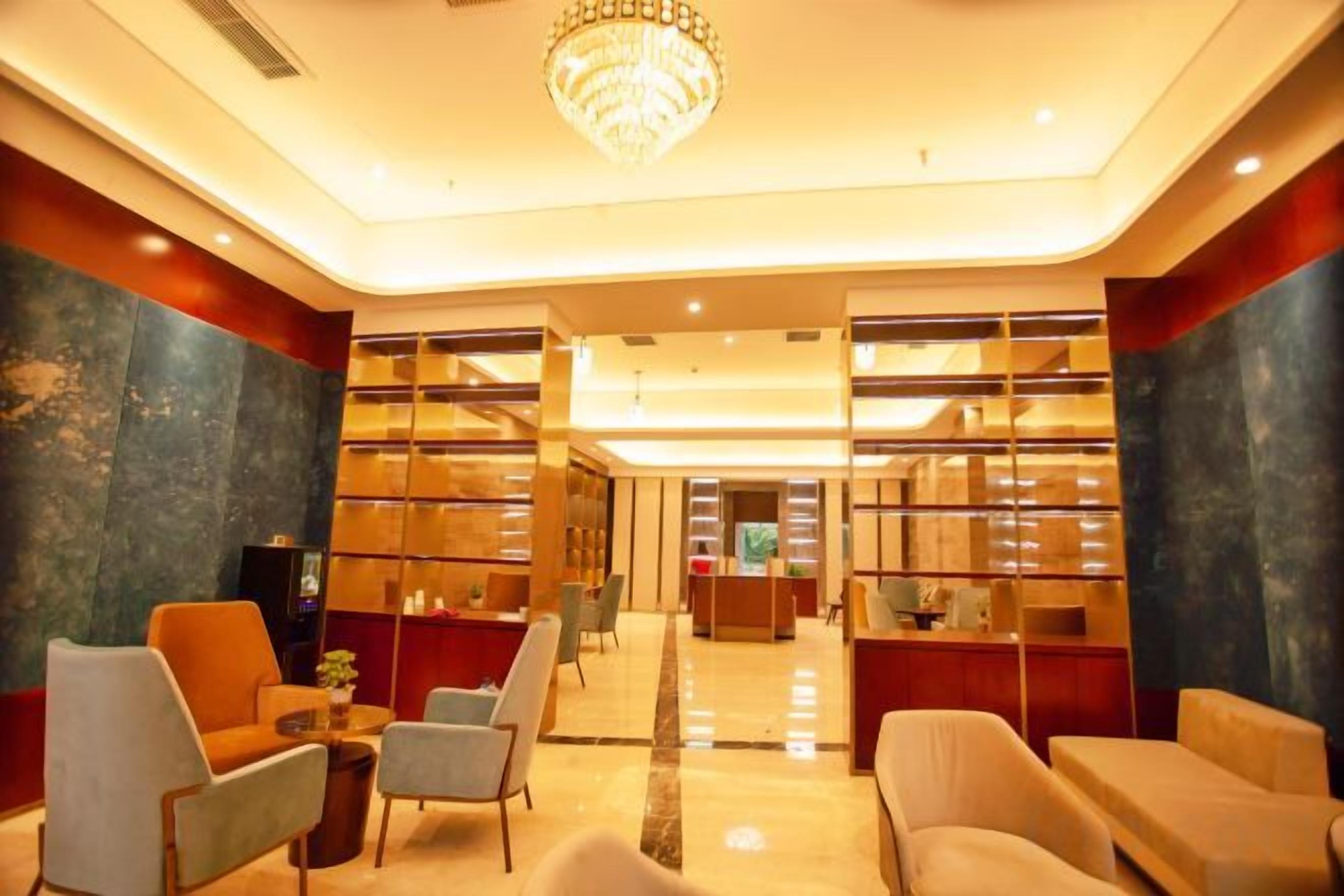 A lobby with seating, a chandelier, and a reception desk.
