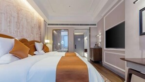 A hotel room with a large bed, a TV, and a desk. - Sheng Shi Jin Hai Grand Hotel (Nayong)