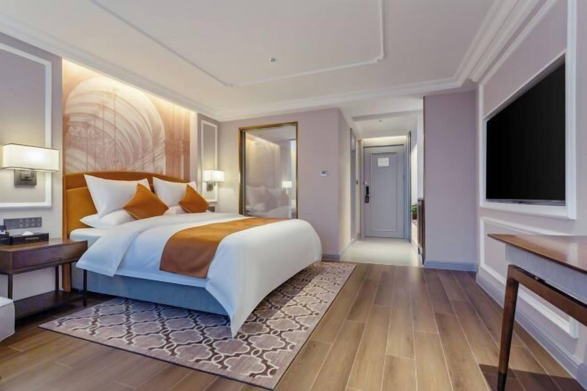 Ein Hotelzimmer mit Bett, Fernseher, Schreibtisch und Spiegel.