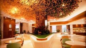 A modern hotel lobby with a central seating area, a decorative ceiling, and a small garden with a deer statue. - Sheng Shi Jin Hai Grand Hotel (Nayong)