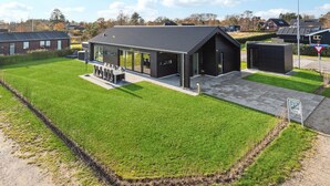 Een modern gebouw met een plat dak, grote ramen en een overdekte patio.