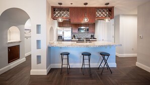 A modern kitchen with a central island, bar stools, and pendant lighting. - Pool-side 2 Bedroom Viera condo! (Henderson)