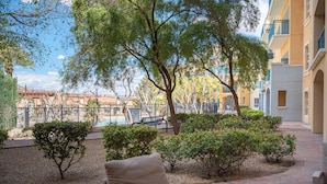 An outdoor patio area with a brick floor, a bench, and a view of a building with balconies. - Pool-side 2 Bedroom Viera condo! (Henderson)