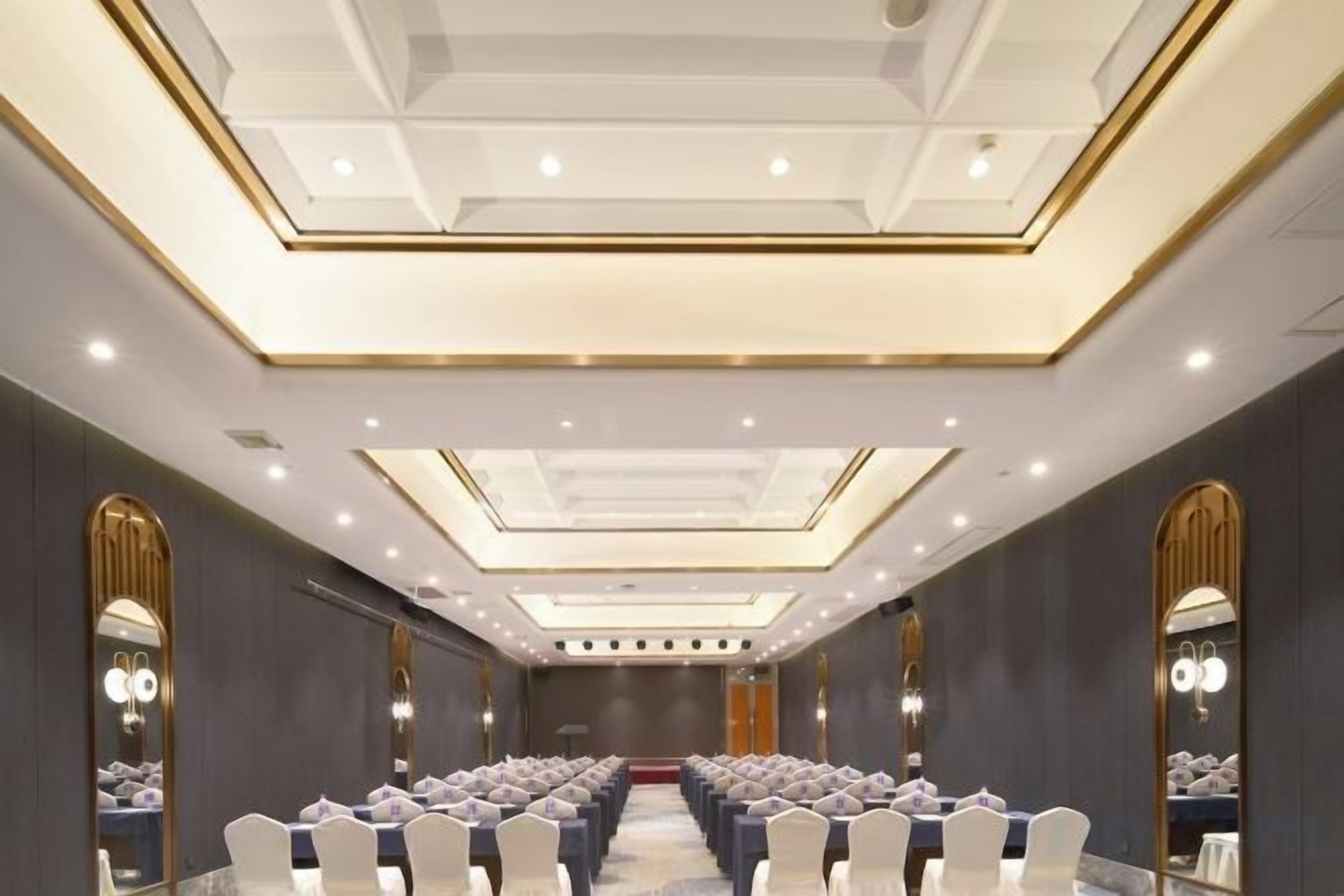 A conference room with rows of chairs, a podium, and a large mirror on the far wall.