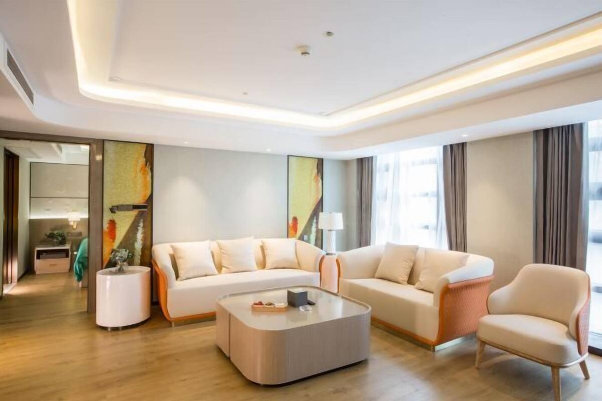 Un salon moderne avec un canapé d’angle, une table basse ronde et un fauteuil.