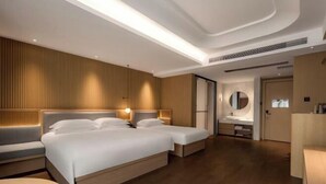 A modern hotel room with a large bed, bedside tables, a vanity with a mirror, and a separate seating area. - Hangzhou Chengbei Relax Hotel (Hangzhou)