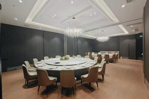 A conference room with a round table, chairs, and a chandelier.