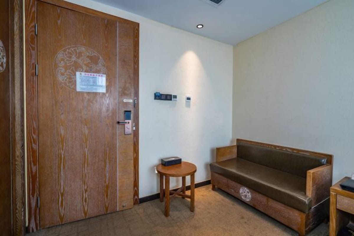 A room with a wooden door, a small round table, and a sofa.