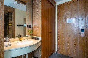 A bathroom with a wooden door, a sink, and a mirror. - Hangzhou Chengbei Relax Hotel (Hangzhou)