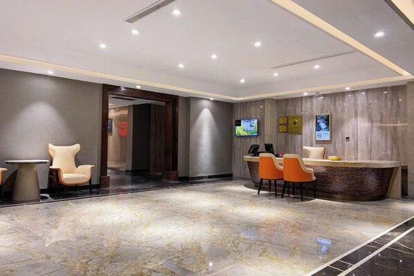 Uma área de recepção moderna com piso de mármore, balcão de atendimento e diversas opções de assento.