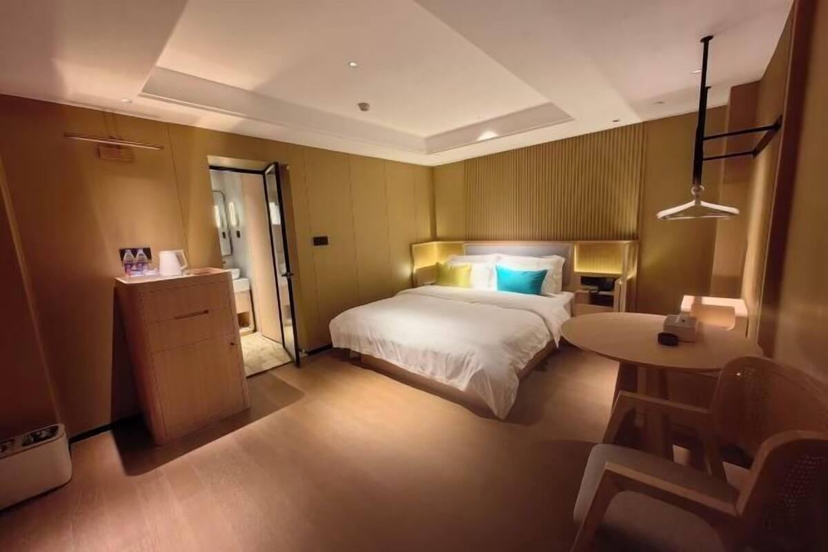 Une chambre d’hôtel comprenant un lit, une table de chevet, une chaise, un bureau et une petite table avec une lampe.