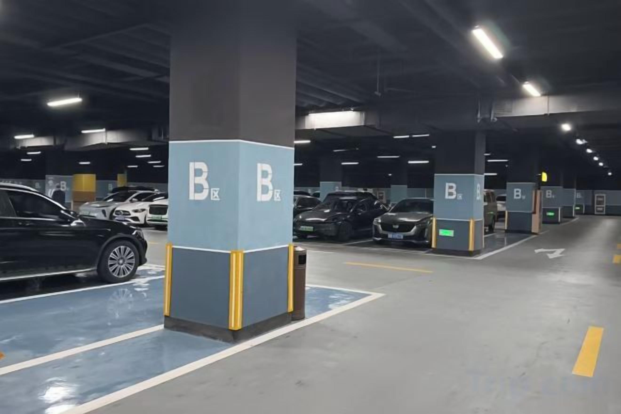 An indoor parking garage with multiple parking bays, each marked with a blue and white sign.