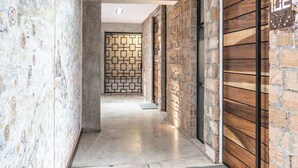 Un passadís amb un mur amb dibuixos, un mur de fusta amb una porta i un paviment de rajoles.