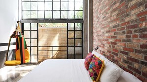 A room with a bed, a colorful hanging chair, and a large window with a view of greenery. - Loft 202 (Puerto Vallarta)