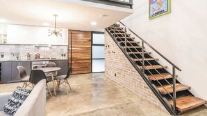 A modern interior with a kitchen, dining area, and staircase. - Loft 202 (Puerto Vallarta)