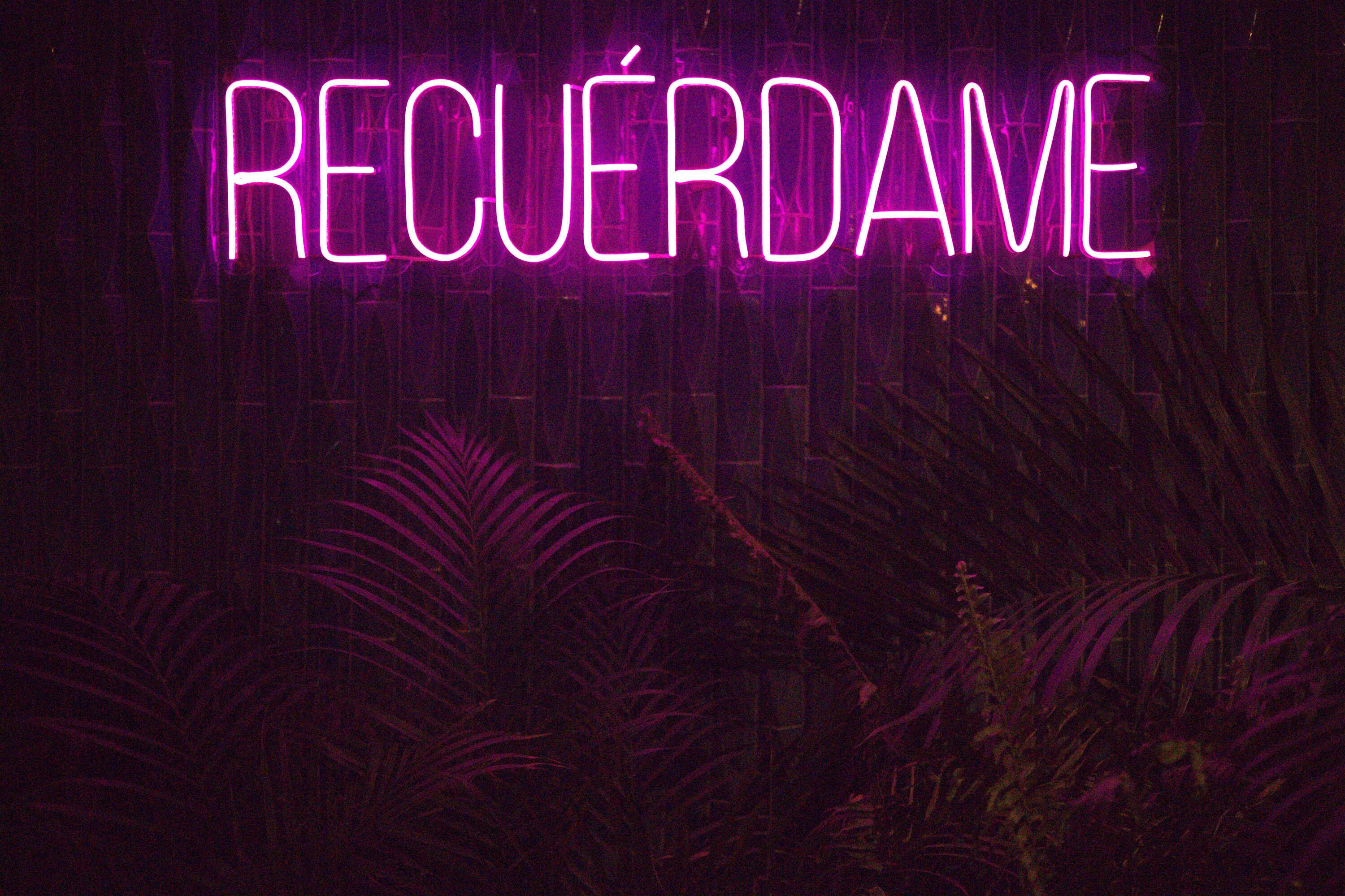 A neon sign with the word "RECUERDA" in a dark setting.