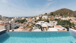 A rooftop pool with a view of a cityscape and a hill in the background. - Room 102 (Puerto Vallarta)