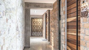 A hallway with a patterned wall on the left, a brick wall on the right, and a wooden wall at the end. - Room 101 (Puerto Vallarta)