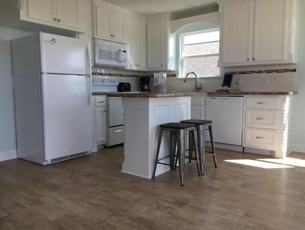 Enjoy cooking in this well-equipped kitchen with a central island, refrigerator, microwave, stove, and dishwasher.