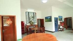 Un'area pranzo con tavolo e sedie in legno, opere d'arte appese alle pareti e una porta con un elemento decorativo.