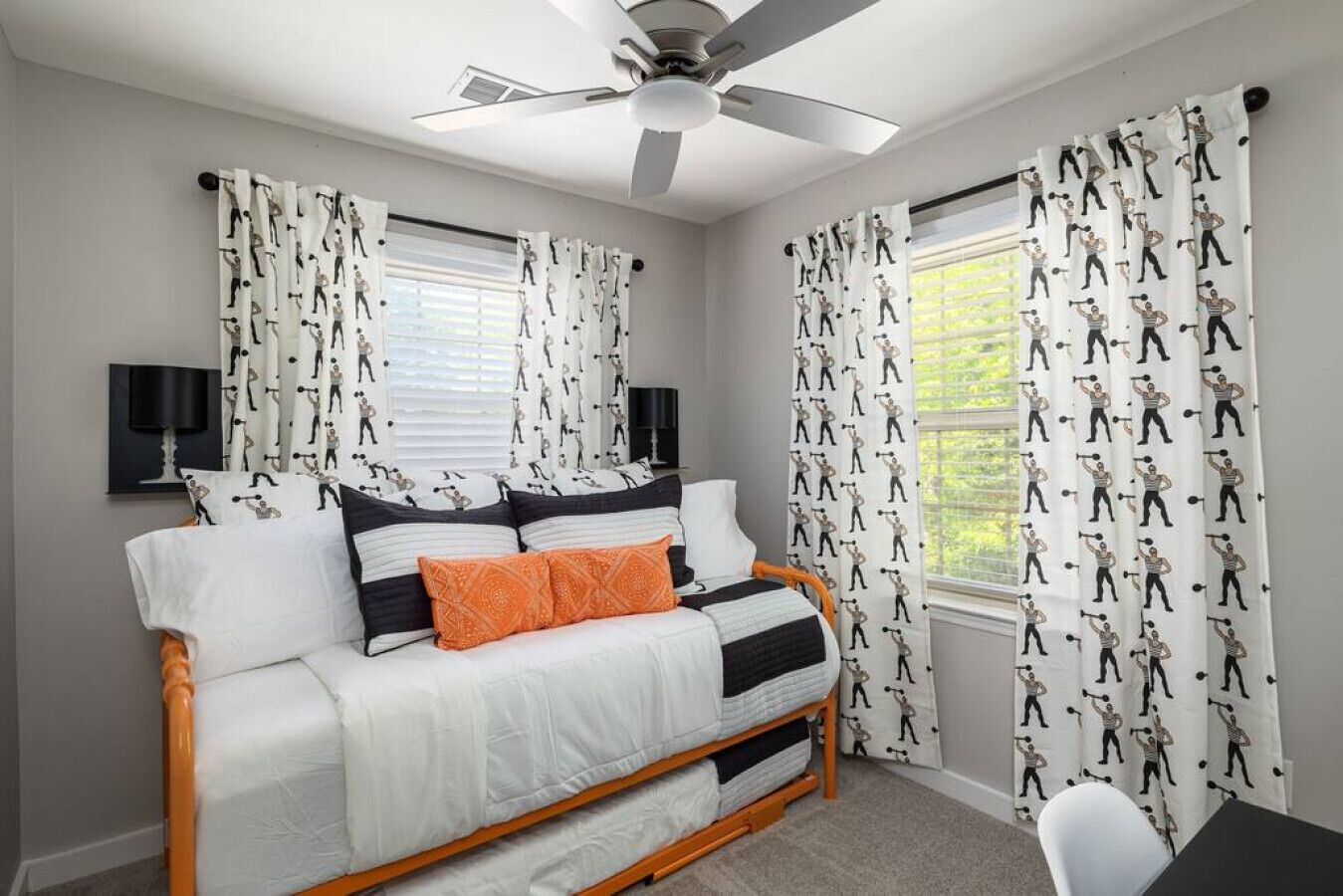 Un dormitorio con cama, cortinas, ventilador de techo y ventana.