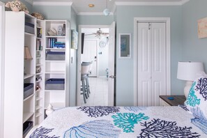 Quarto com cama, guarda-roupa, porta para outro cômodo e mesa de cabeceira com abajur.