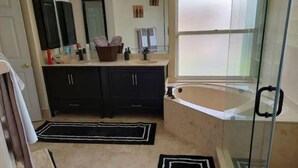Une salle de bain avec une baignoire, une cabine de douche en verre et un meuble-lavabo avec un évier et un miroir.