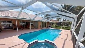 Une piscine intérieure dotée d’un jacuzzi hexagonal au centre, entourée d’une terrasse couverte offrant une vue sur un immeuble d’habitation en arrière-plan.