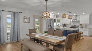 A modern kitchen with a central island, pendant lighting, and a dining area with a bench. - Lake house retreat. (Inverness)
