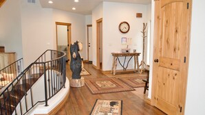 A wooden staircase with a black railing, a bear statue, and a wooden door. - Beautiful home on the 10th green on Priest Lake Golf Course (Priest Lake)