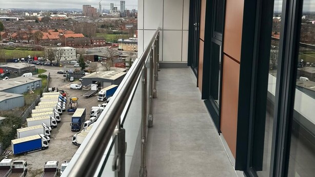Ein Balkon mit Blick auf einen Parkplatz und Gebäude.