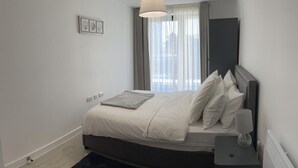 Ein modernes Schlafzimmer mit Bett, Nachttisch und einem Fenster mit Vorhängen.