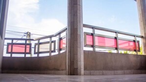 Un vaste atrium moderne doté d’un sol en béton poli et d’une balustrade en verre donnant sur une zone aux teintes rouges.