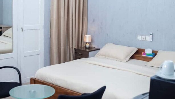 Une chambre d’hôtel comprenant un lit, une table de chevet, une lampe et une petite table avec une chaise.