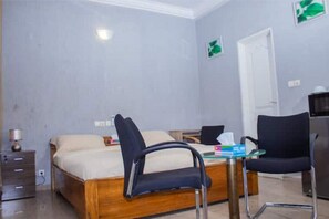 A bedroom with a wooden bed, a desk, two chairs, and a small table. - Studio cosy et confortable (Lomé)