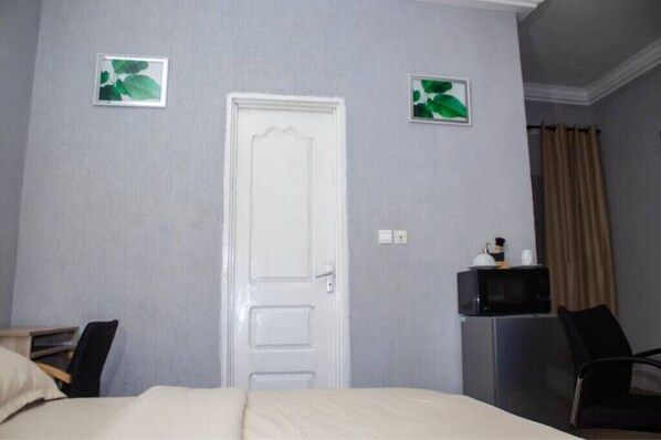 A hotel room with a bed, a desk, a chair, a television, and a door.