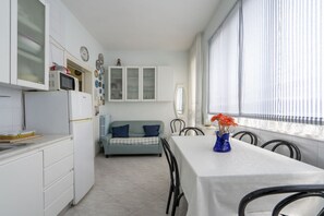 Een compacte keuken met een eethoek, een bank en een tafel met een vaas.