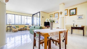 A spacious living room with a dining table, sofas, and a TV. - GuestHost - Grazia Attic Apartment with terrace (Trani)