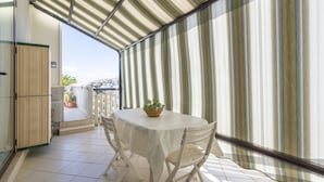 A balcony with a table and chairs, a potted plant, and a view of the city. - GuestHost - Grazia Attic Apartment with terrace (Trani)