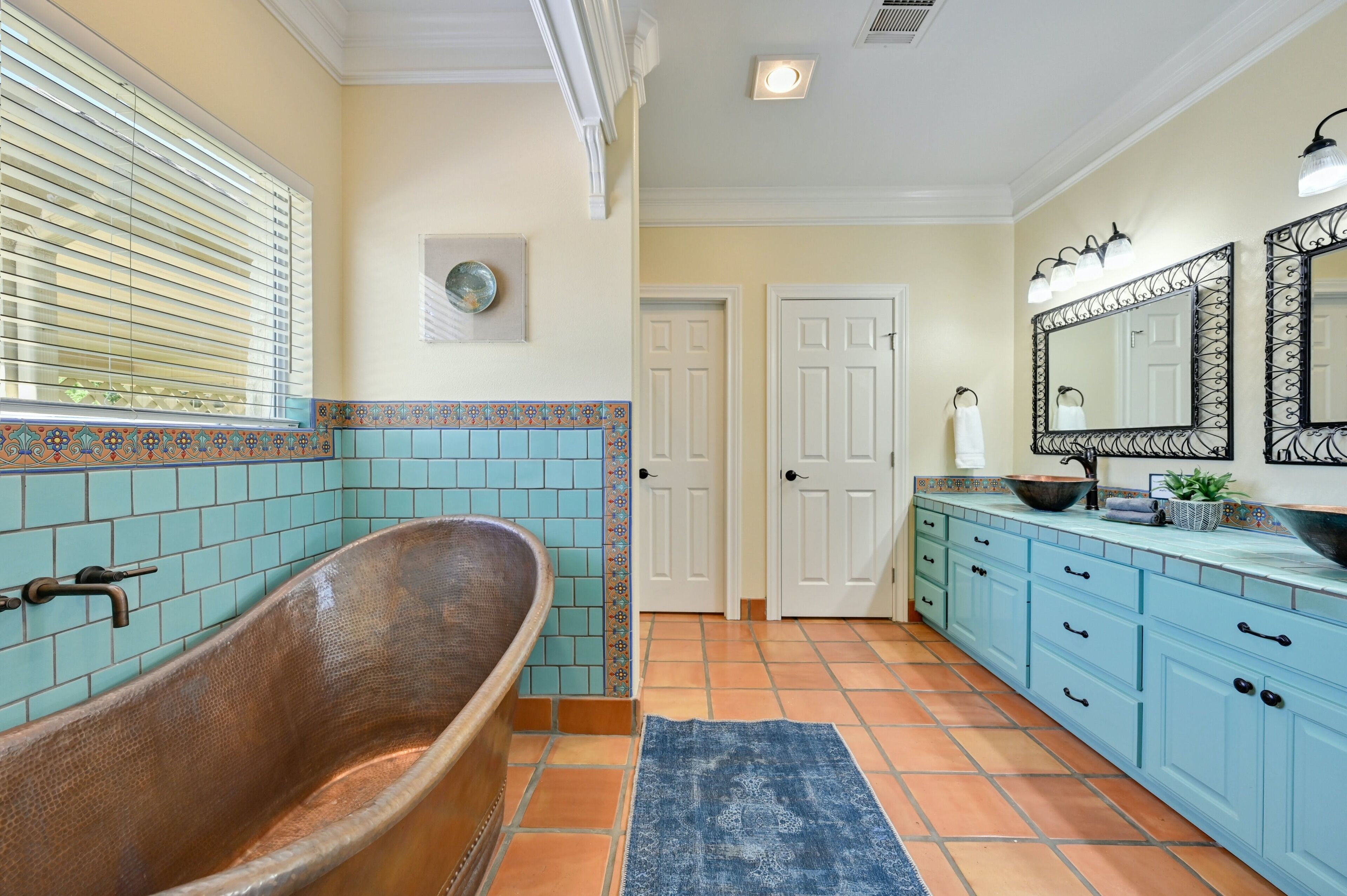 A bathroom with a freestanding bathtub, a sink with a large mirror, and a door leading to another room.