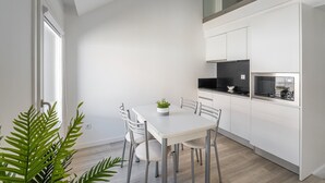 Una cocina moderna con armarios blancos, encimera negra y una ventana pequeña.