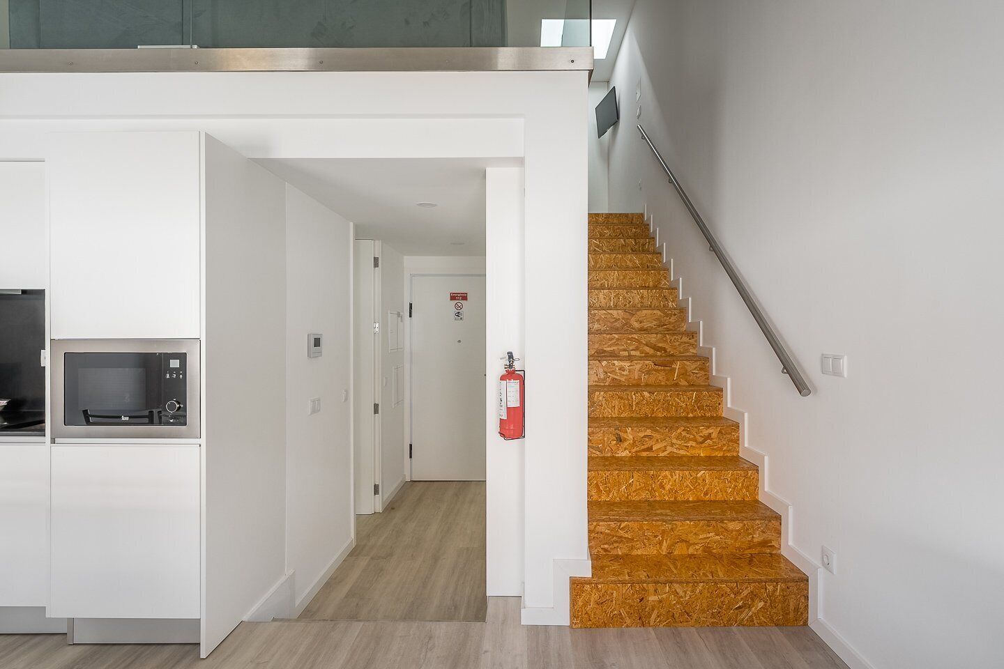 A modern kitchen with built-in appliances and a staircase with wooden steps.