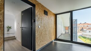 Un interior moderno con una puerta oscura, un revestimiento de pared de madera y un ventanal que ofrece vistas a edificios.
