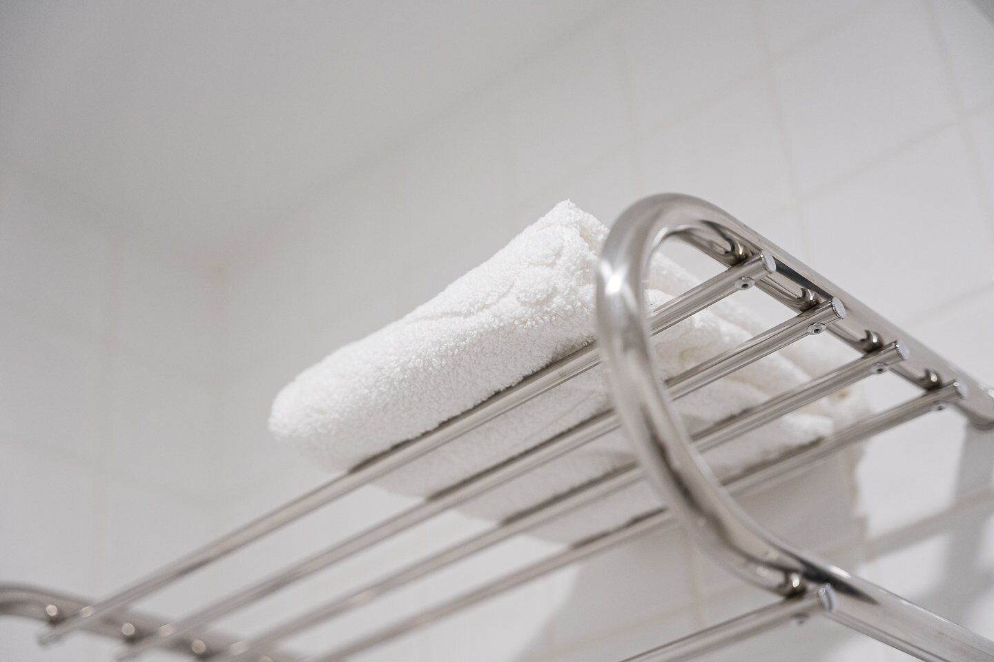 Una toalla blanca sobre un perchero metálico en un baño.