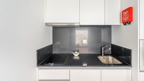 Una cocina moderna con encimera negra, pileta de acero inoxidable y muebles bajos blancos.
