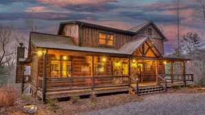 Eine Holzhütte mit Veranda, mehreren Fenstern und einer Treppe zum Eingang.