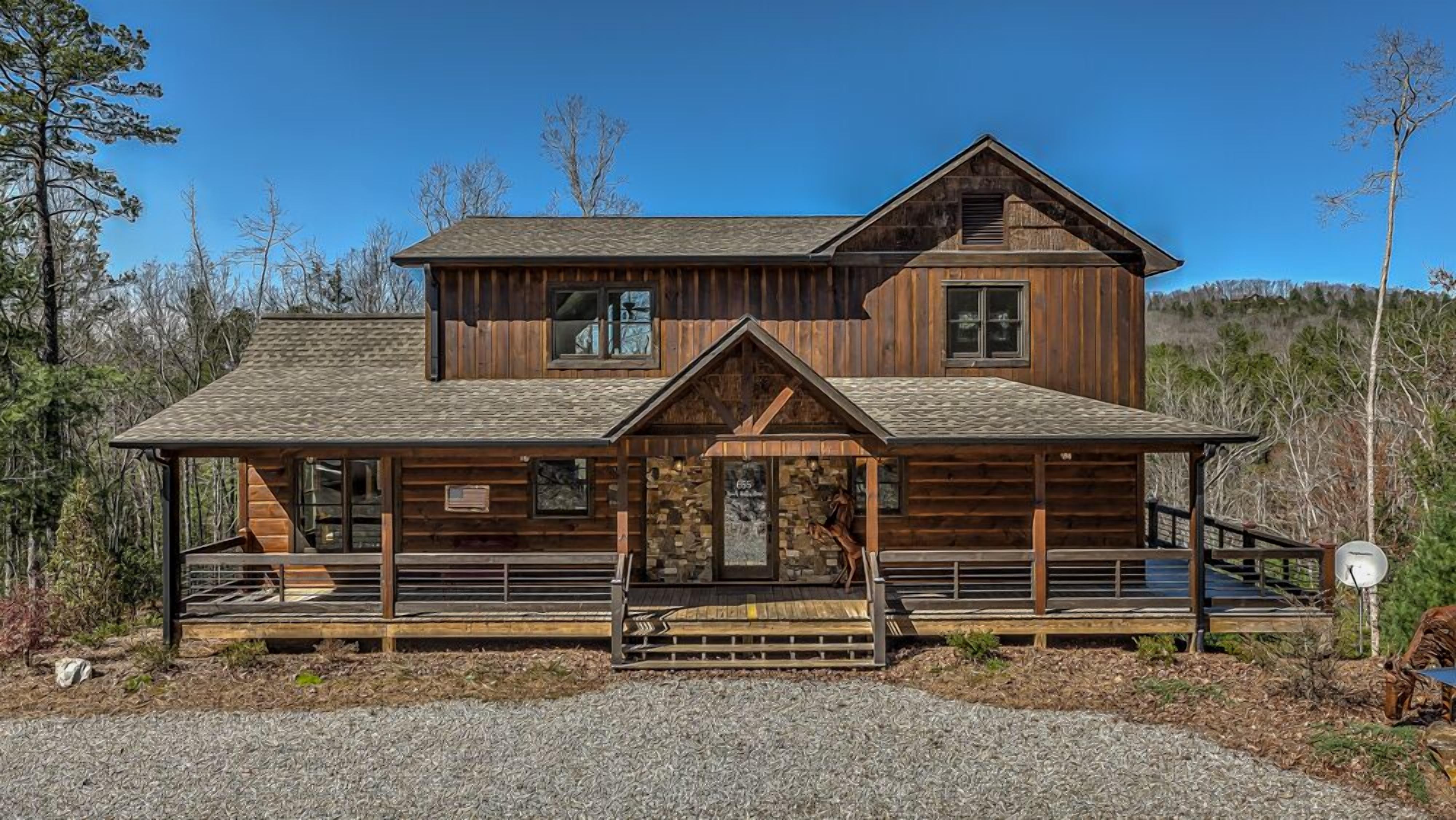A two-story log cabin with a porch and a covered deck area.